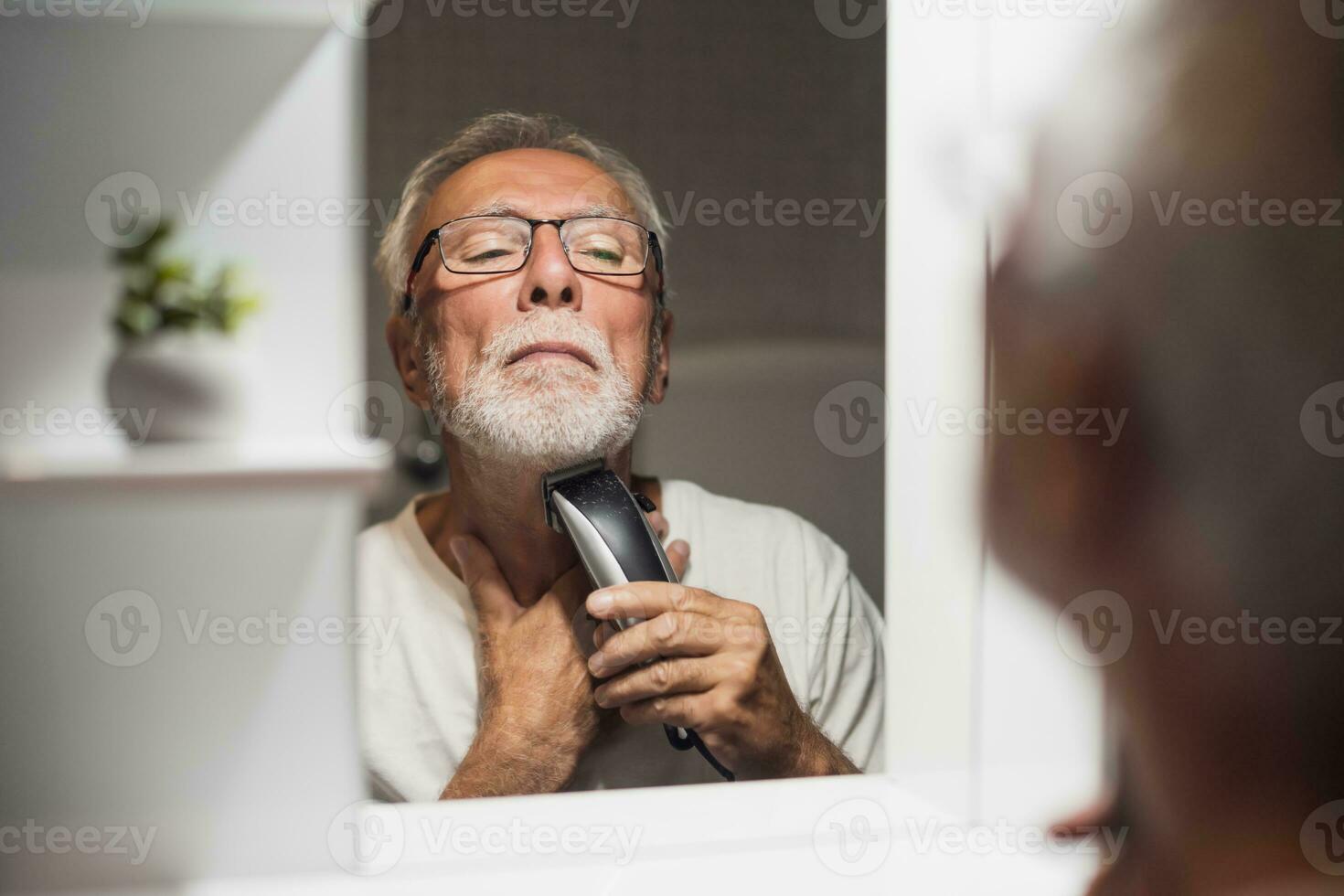 A senior man trims his beard photo