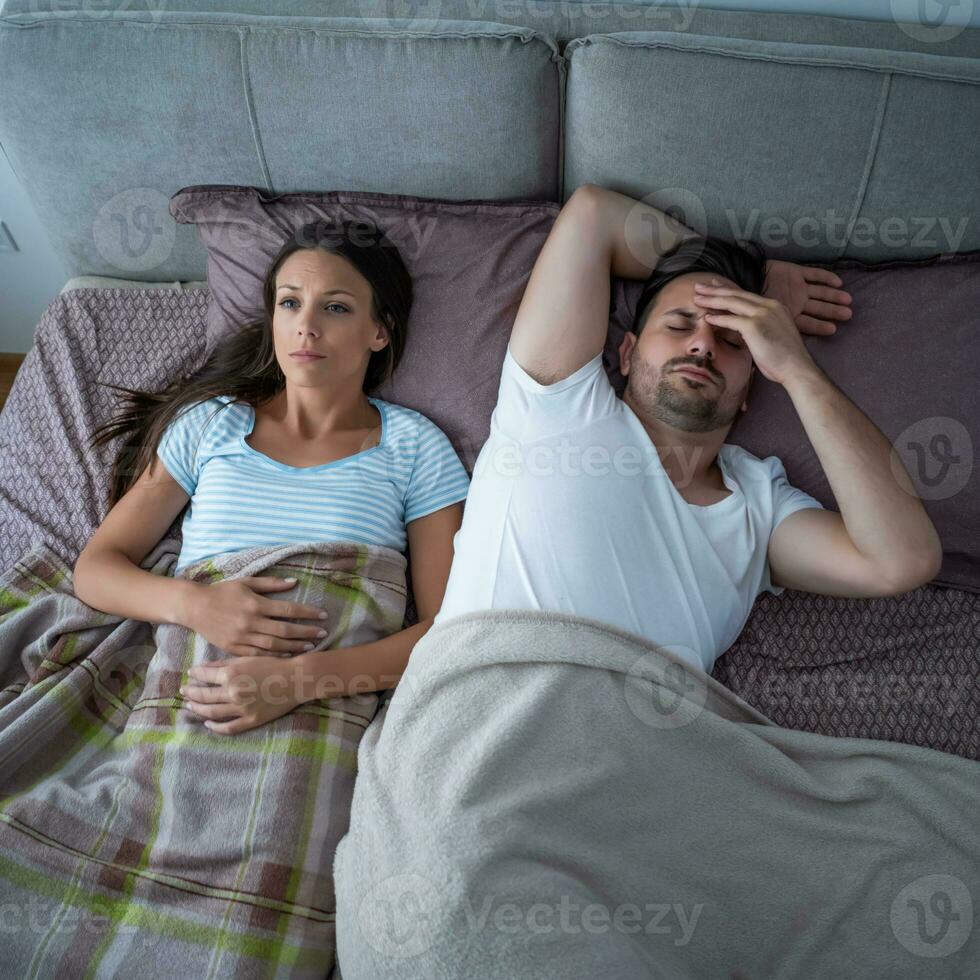 A young couple lying in bed with relationship issues photo