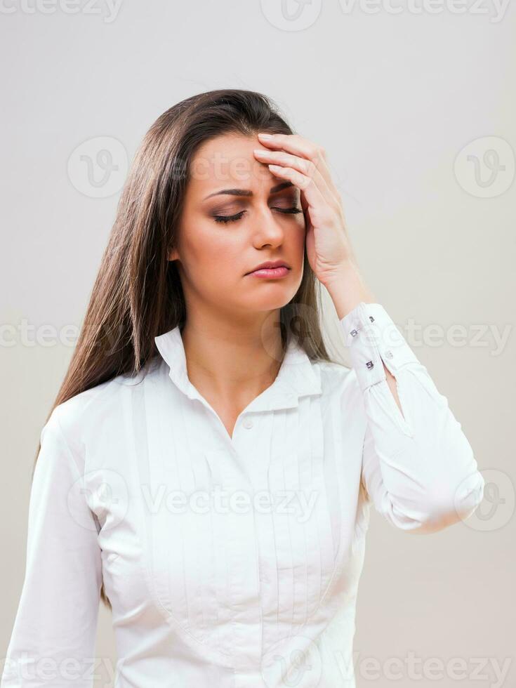 un mujer en un blanco camisa con un dolor de cabeza foto