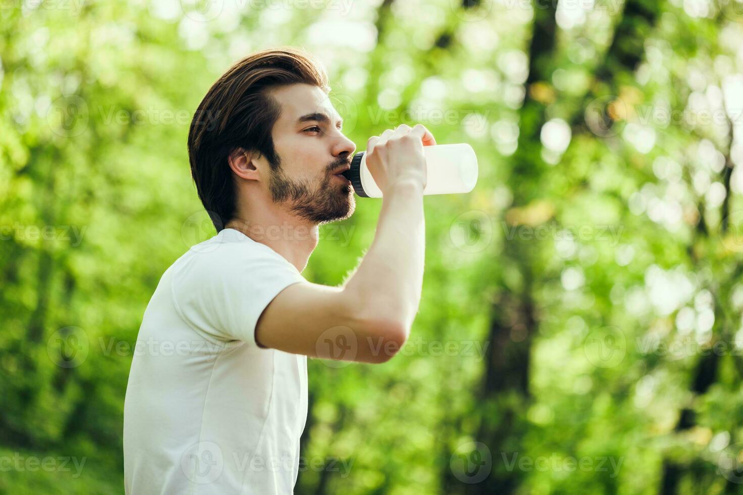 un hombre Bebiendo agua después haciendo físico ejercicios foto