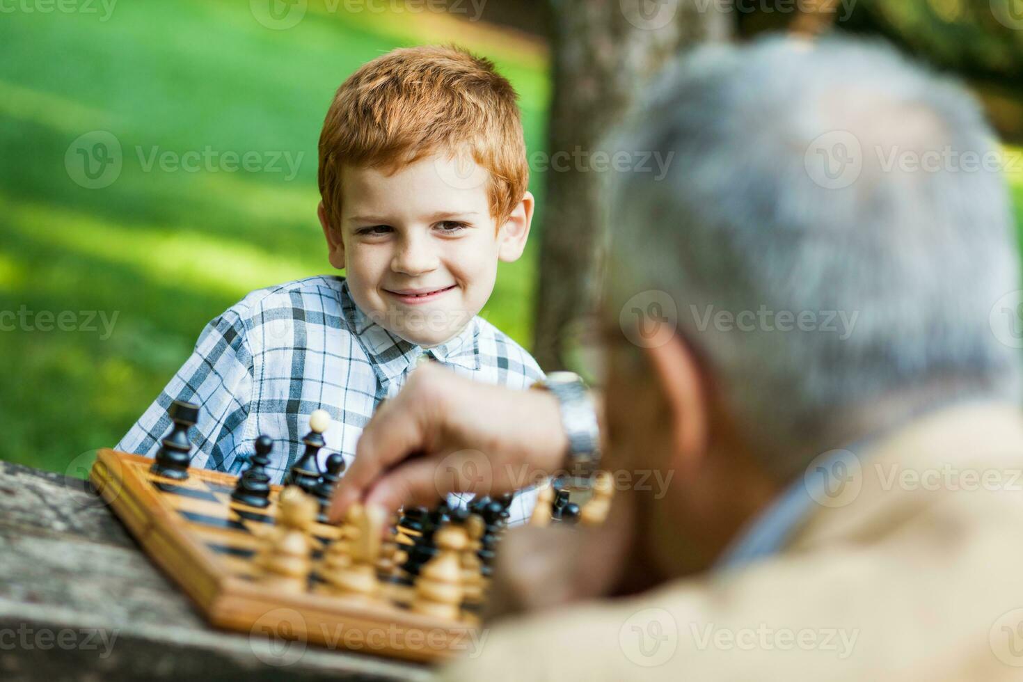 A grandfather and his grandson playing chess photo