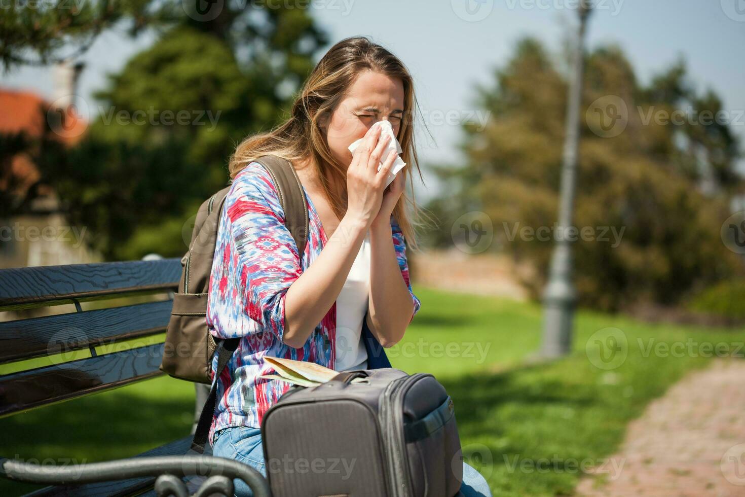 Young tourist woman blowing her nose on the park photo