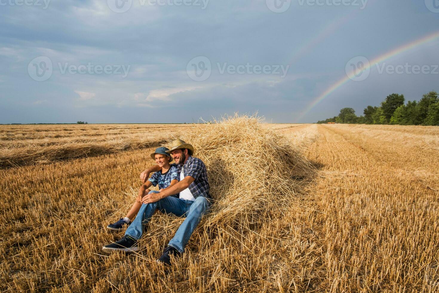 Father and son are standing in their wheat field after a successful harvest. photo