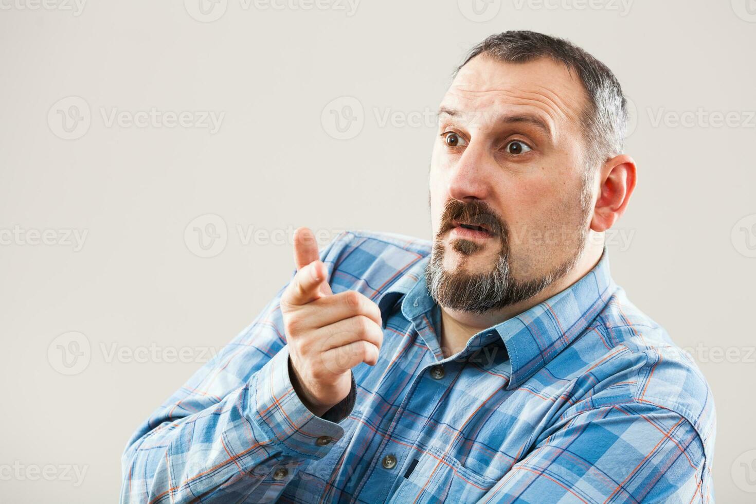 A man with a blue plaid shirt making a face photo