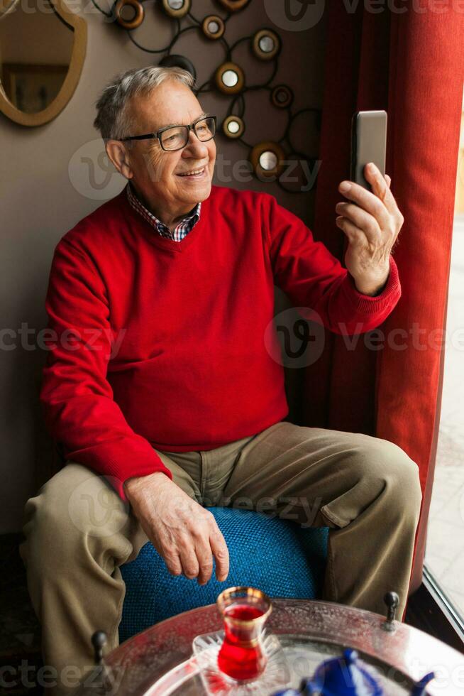 A senior man in a red sweater relaxing photo