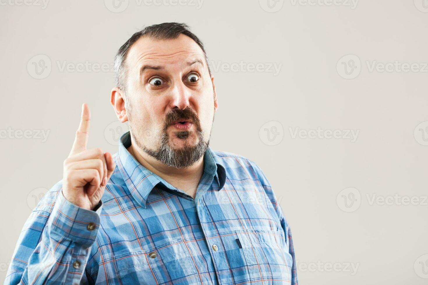 A man with a blue plaid shirt making a face photo