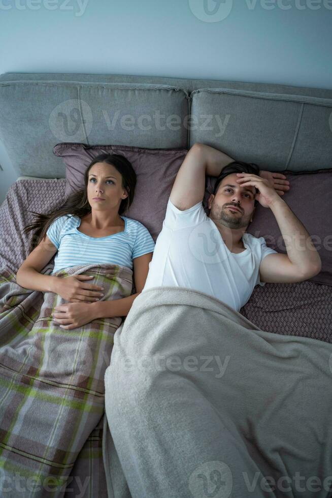 A young couple lying in bed after an argument photo
