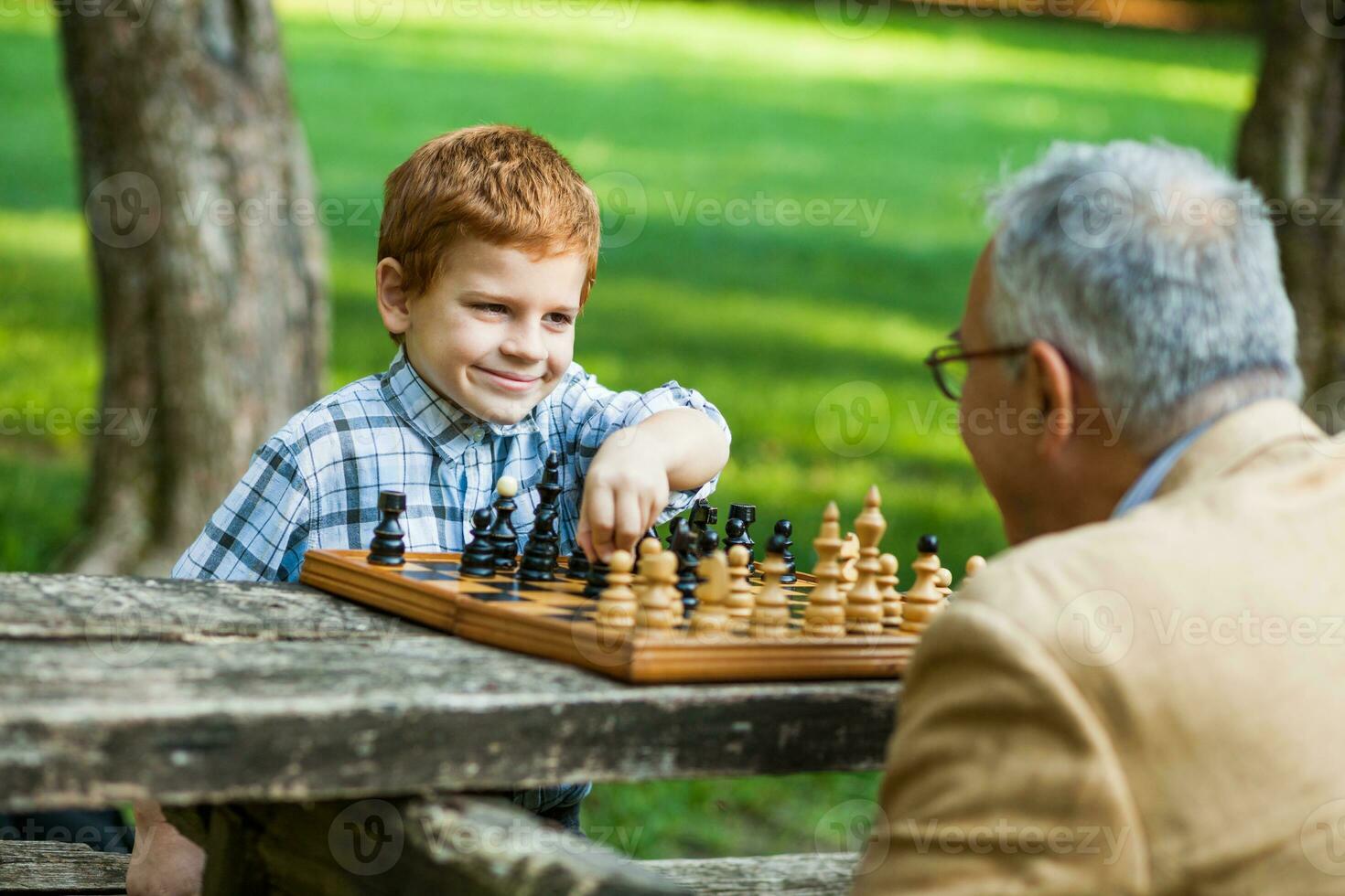 A grandfather and his grandson playing chess photo