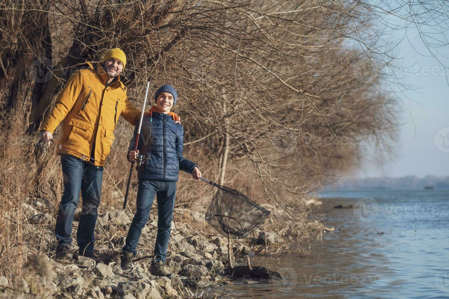 Father and son are fishing on sunny winter day photo