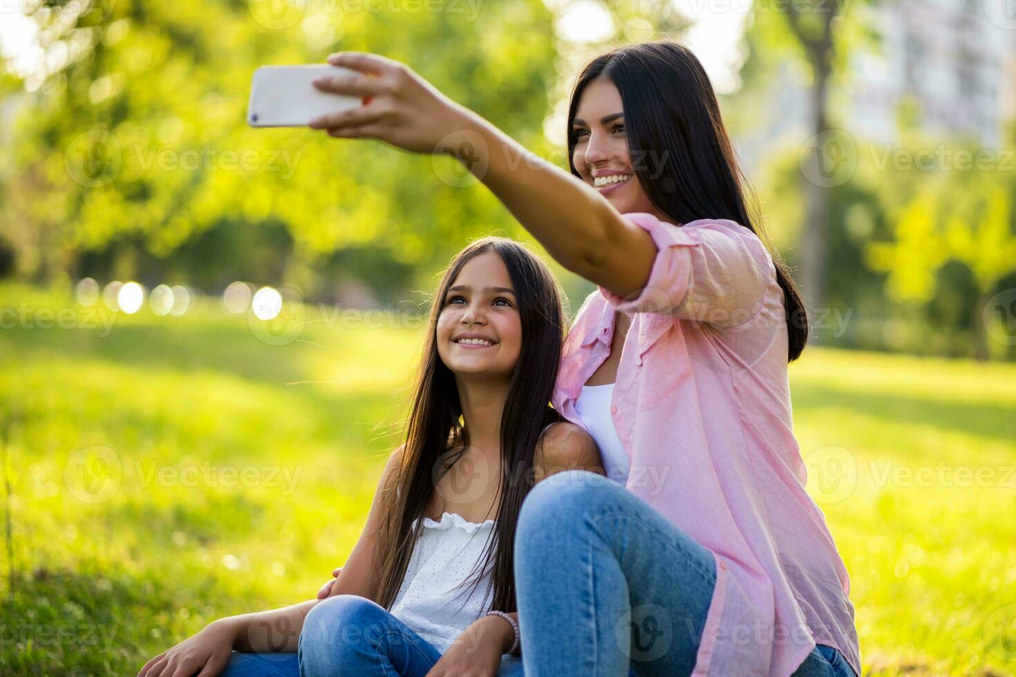 Mother and daughter taking a selfie at the park photo