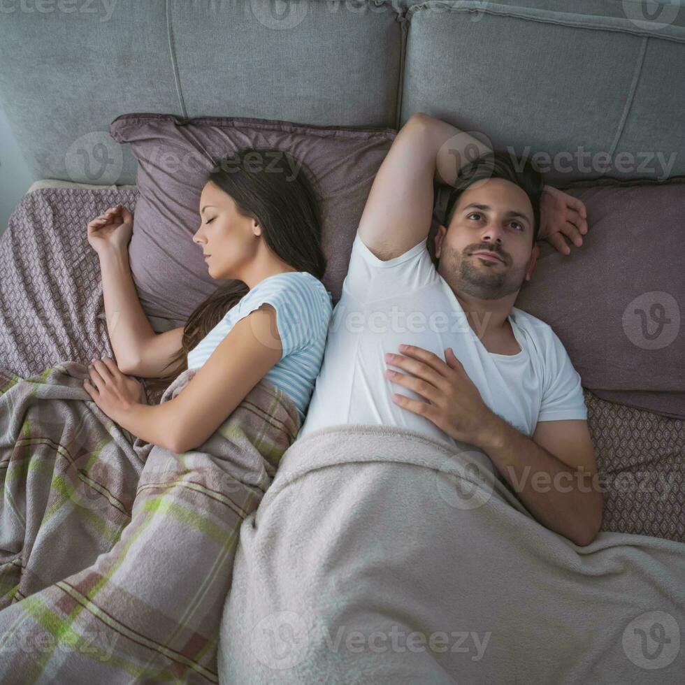 A young couple lying in bed with relationship issues photo