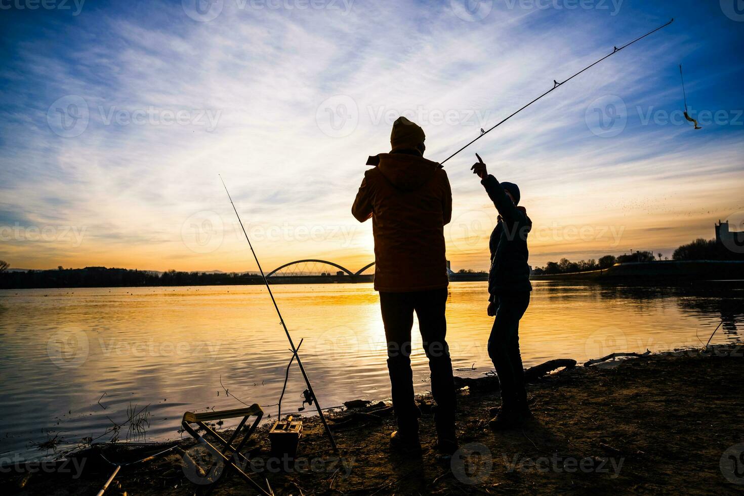 Father and son are fishing on sunny winter day photo