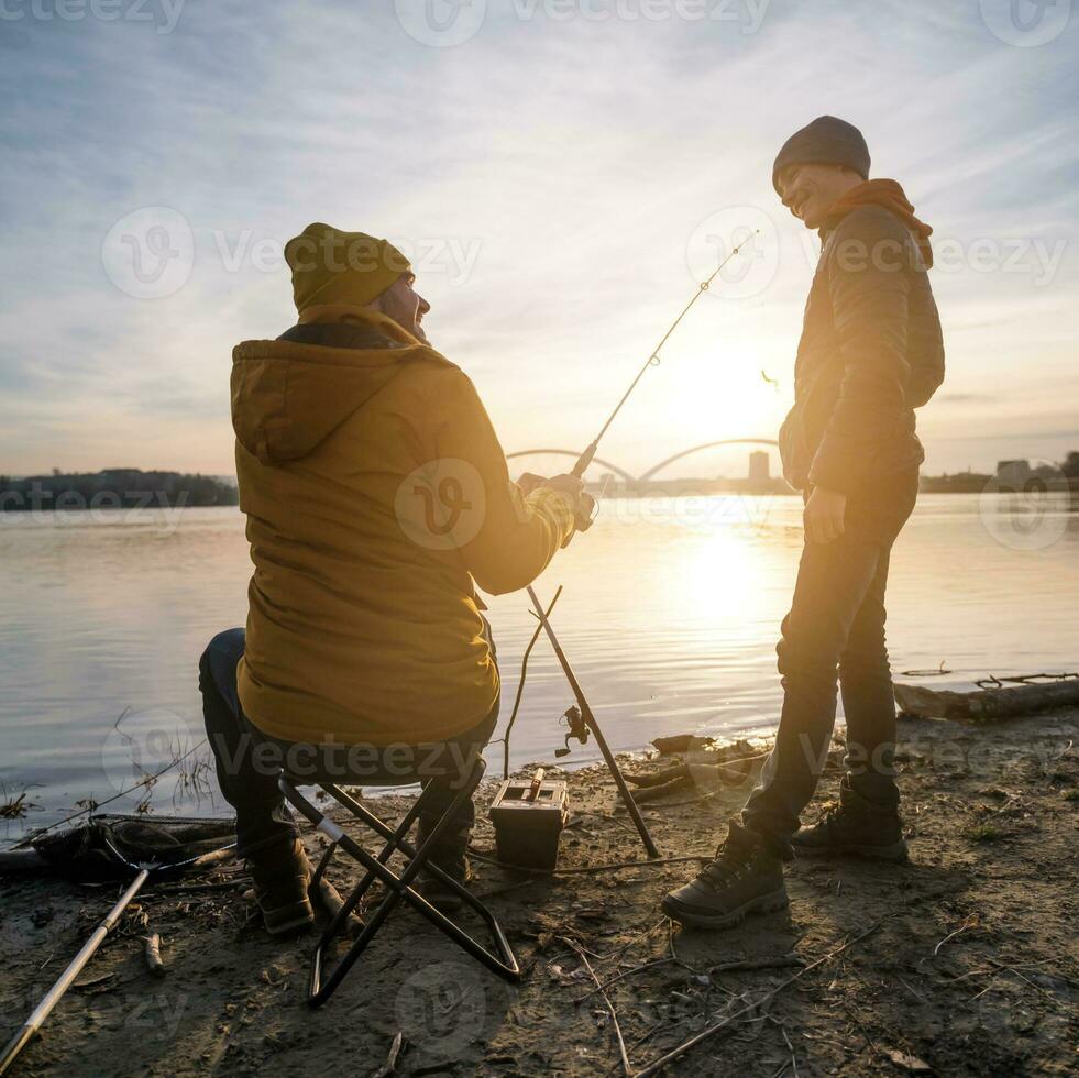 Father and son are fishing on sunny winter day photo