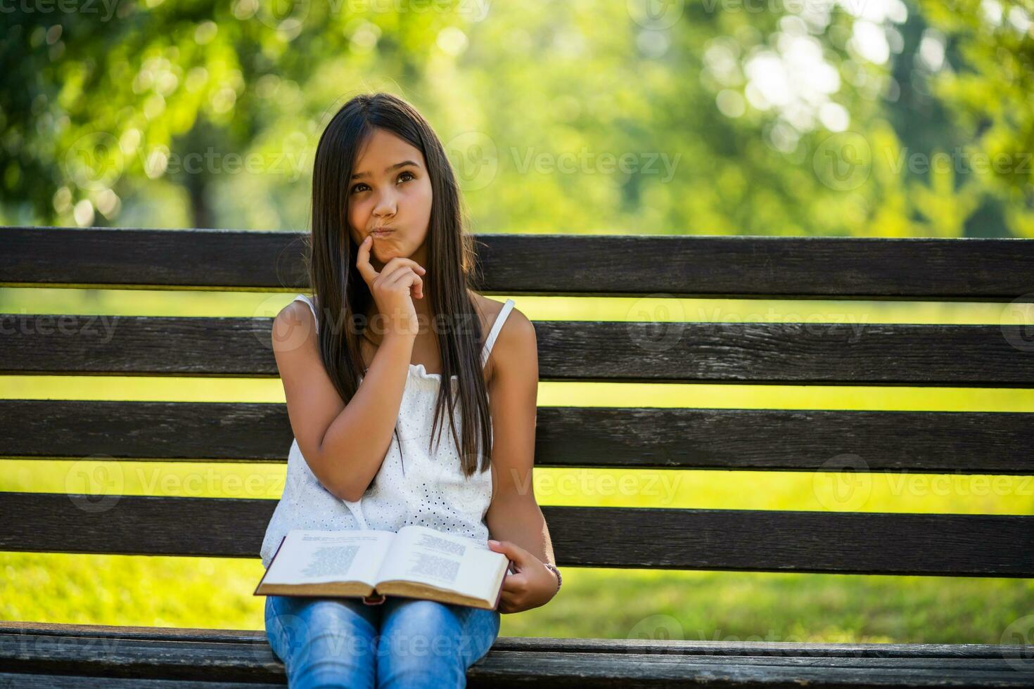 Little girl reading on the park photo