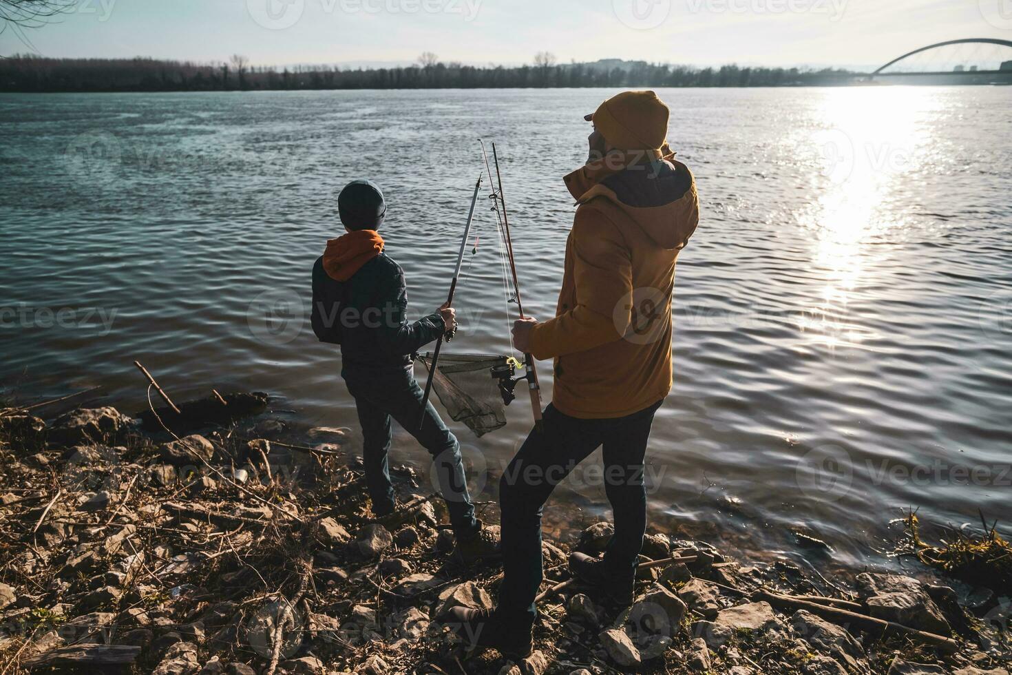 Father and son are fishing on sunny winter day photo