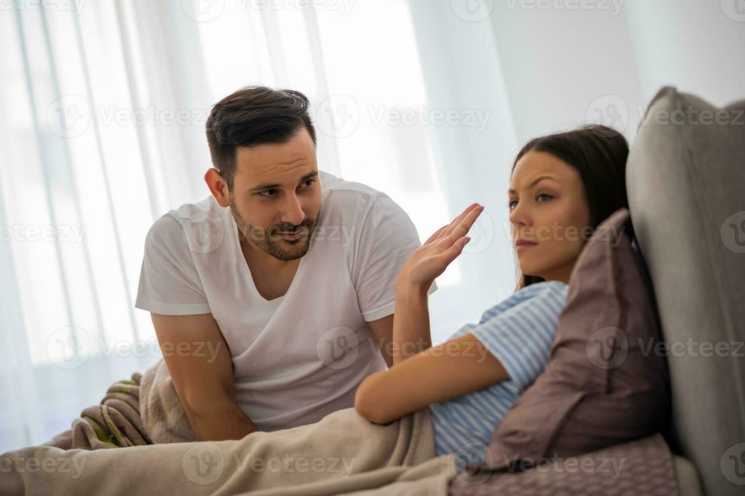 A young couple lying in bed with relationship issues photo