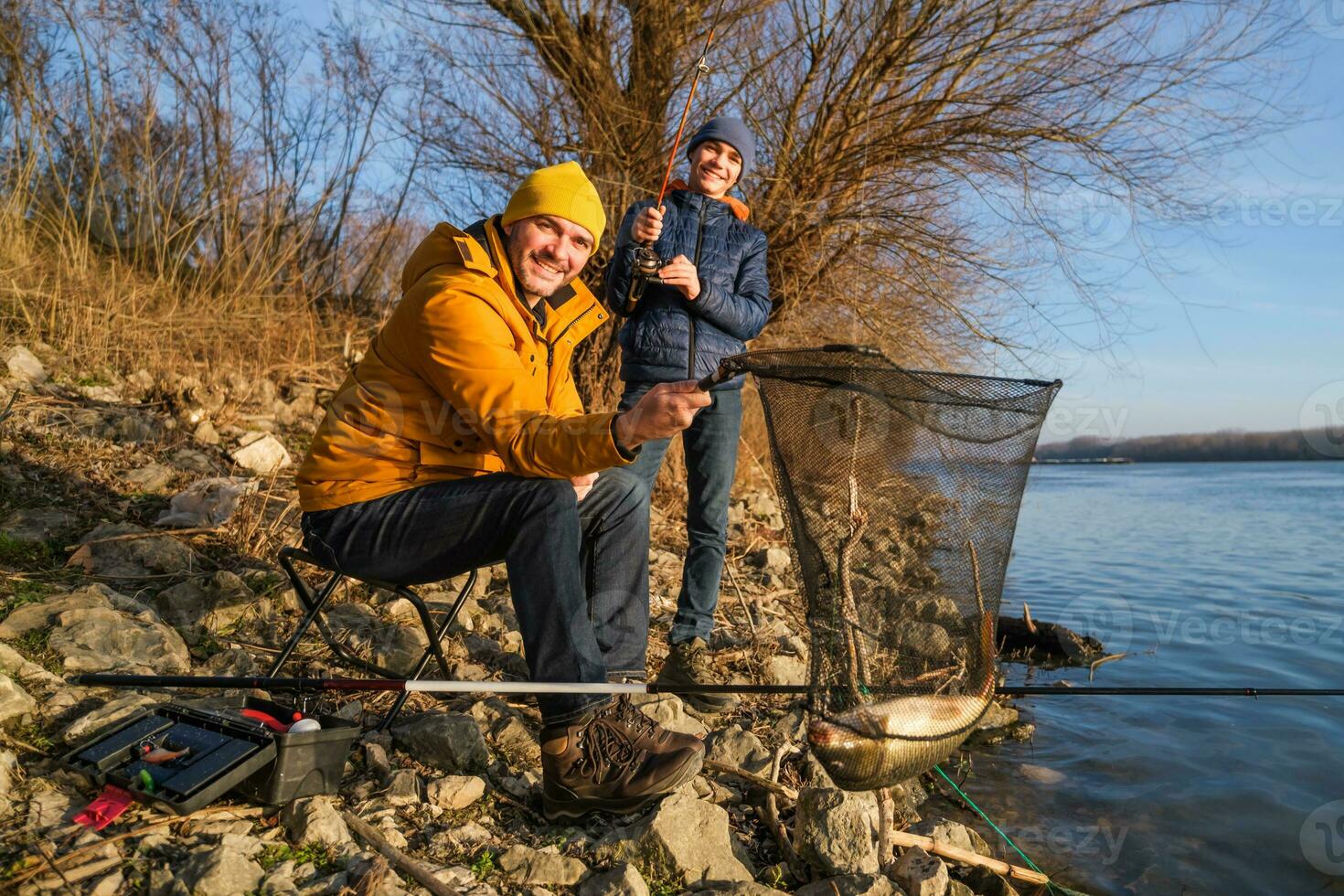 Father and son are fishing on sunny winter day photo