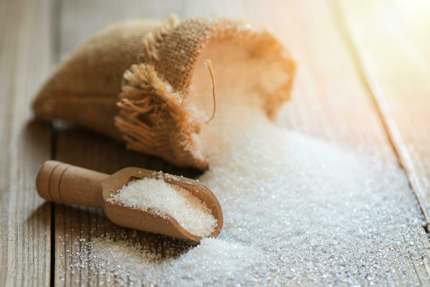 blanco azúcar para comida y dulces postre caramelo montón de dulce azúcar cristalino granulado, azúcar en saco y de madera antecedentes foto