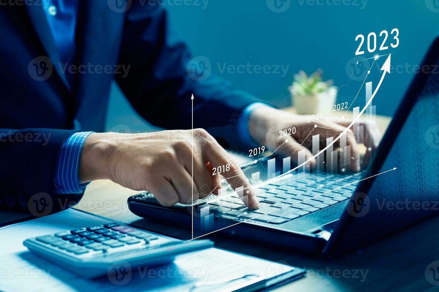 Businessman planning 2023 business growth on desk with virtual hologram chart graph. Calculate income and profit on investments and an increase in the indicators of positive growth, Return on Stocks photo