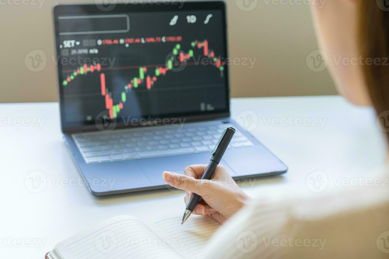 Investor analyzing exchange market, asian young business woman trader on graphic charts on laptop computer, writing analyze data, information in notebook for trading stock at screen with diagrams. photo