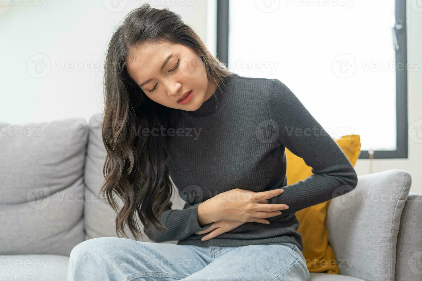 Flatulence asian young woman, girl hand in stomach ache, suffer from food poisoning, abdominal pain and colon problem, gastritis or diarrhoea. Patient belly, abdomen or inflammation, concept. photo