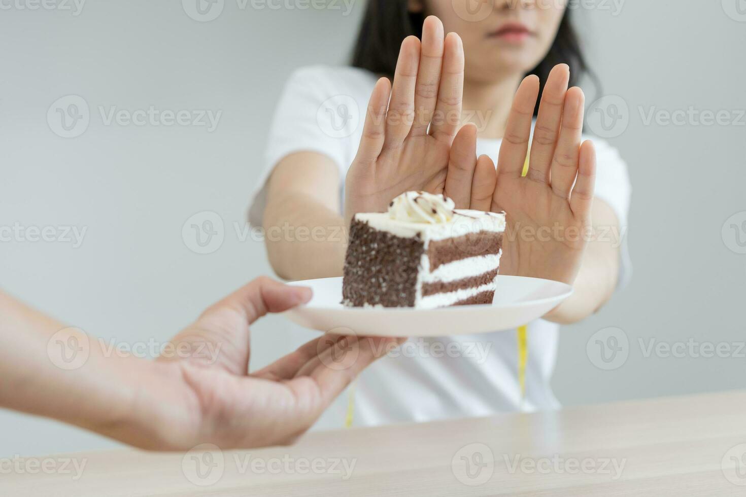 Diet, Dieting unhealthy asian young woman hand in push out, rejecting eat chocolate cake or sweet taste, fighting to keep it from getting fat when person bring to me. Healthy, nutrition of weight loss photo