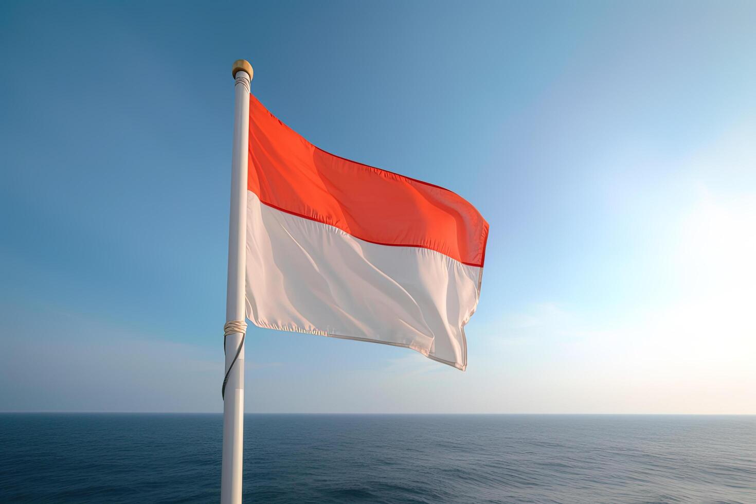 Indonesia national flag waving in the blue sky on the ocean background. Red and white flag with clouds. photo