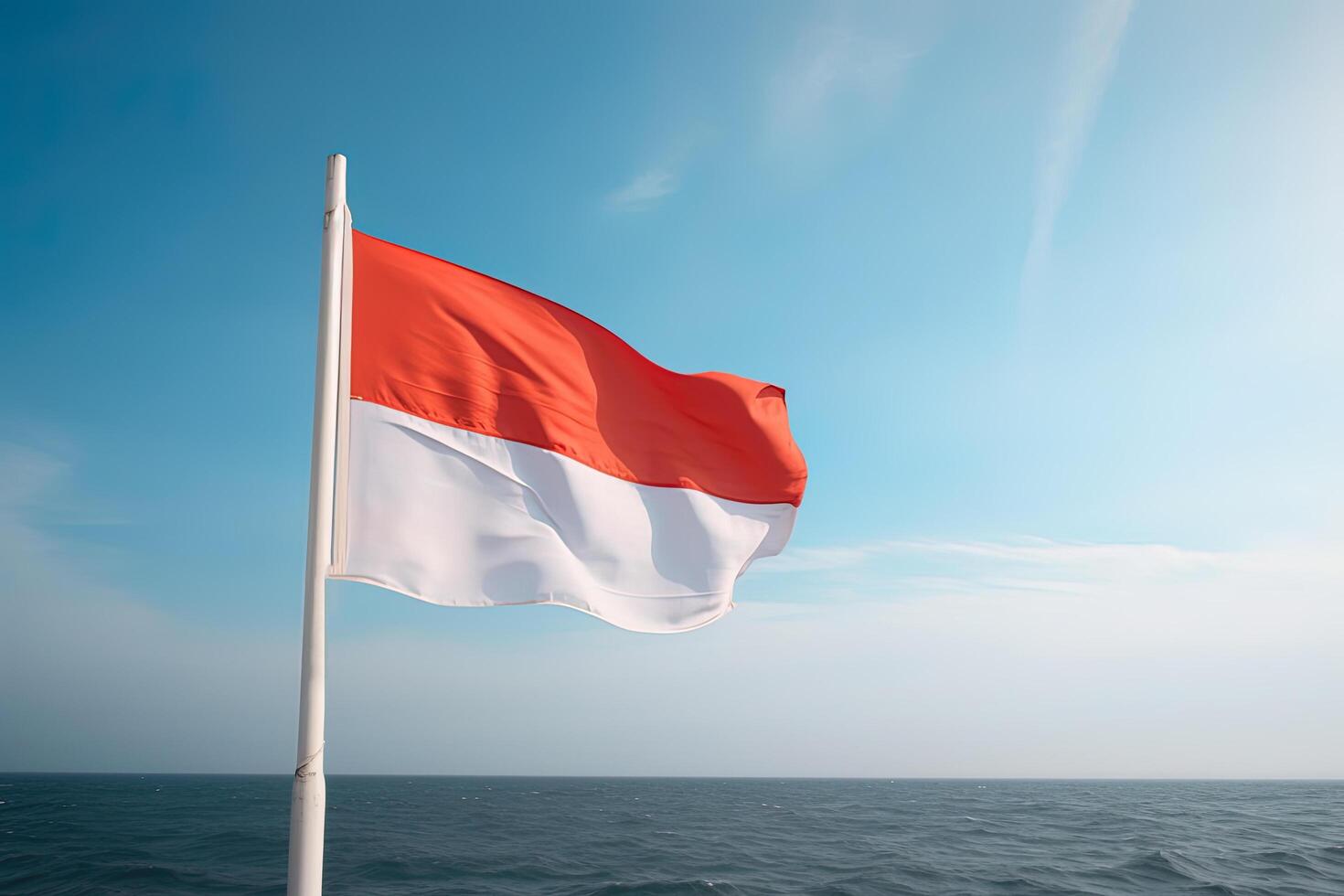 Indonesia national flag waving in the blue sky on the ocean background. Red and white flag with clouds. photo