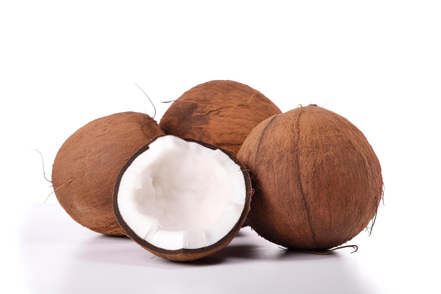 a whole and a half coconut on a white surface. photo