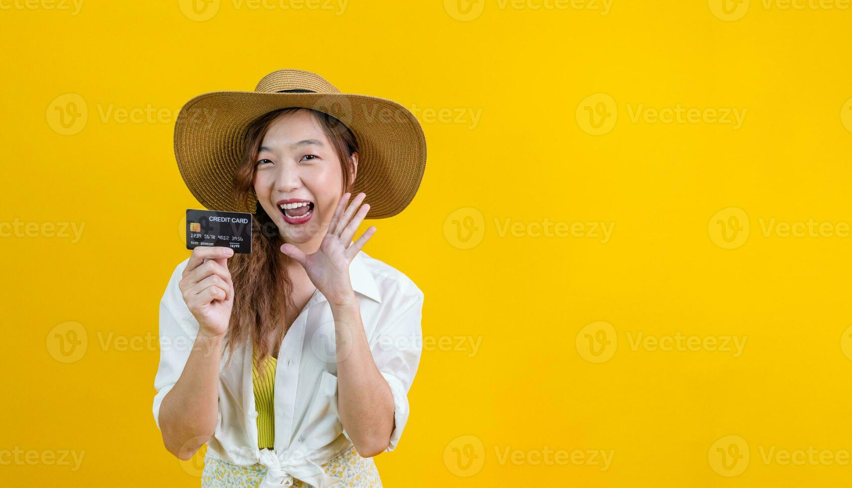 retrato de joven asiático mujer en casual playa ropa con crédito tarjeta es narración o hablando acerca de rebaja promoción aislado en amarillo antecedentes para viaje y Moda estudio cortar fuera foto