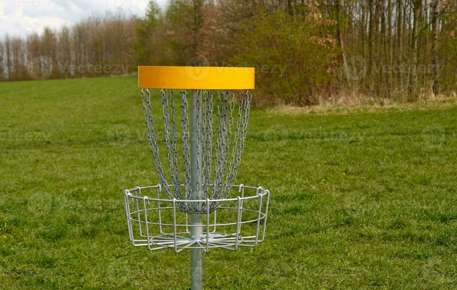 Disc Golf basket. Frisbee golf is sport and hobbie in outdoor park. Metal basket with chains for disc game surrounded by vibrant green trees. photo