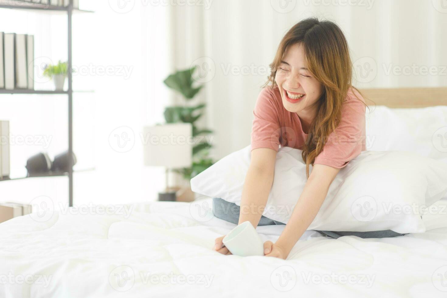 Portrait young adult asian woman sitting on bed with happy face after wake up in morning photo