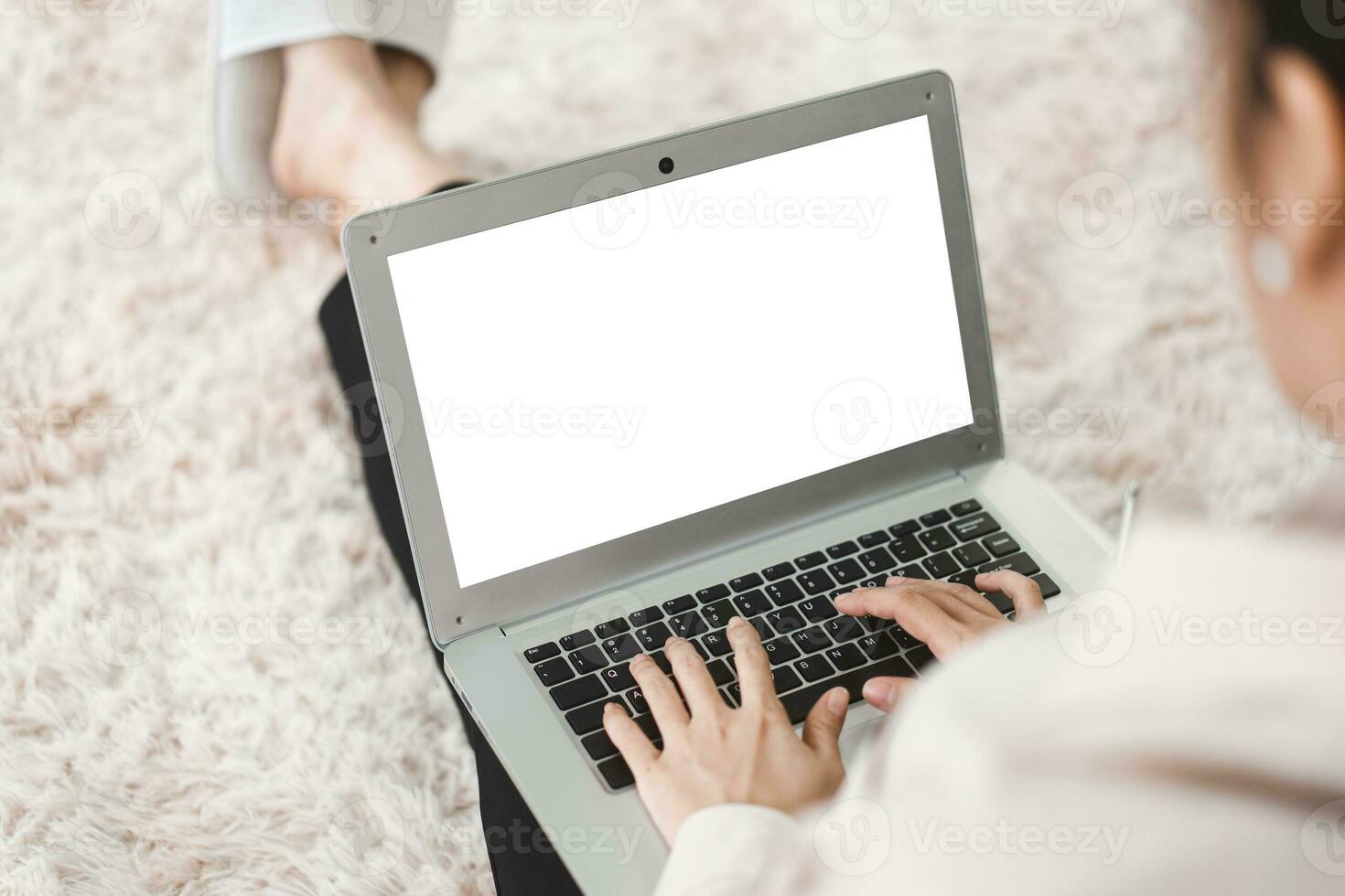 Blank white screen laptop with woman hand typing keyboard from back shoulder view photo