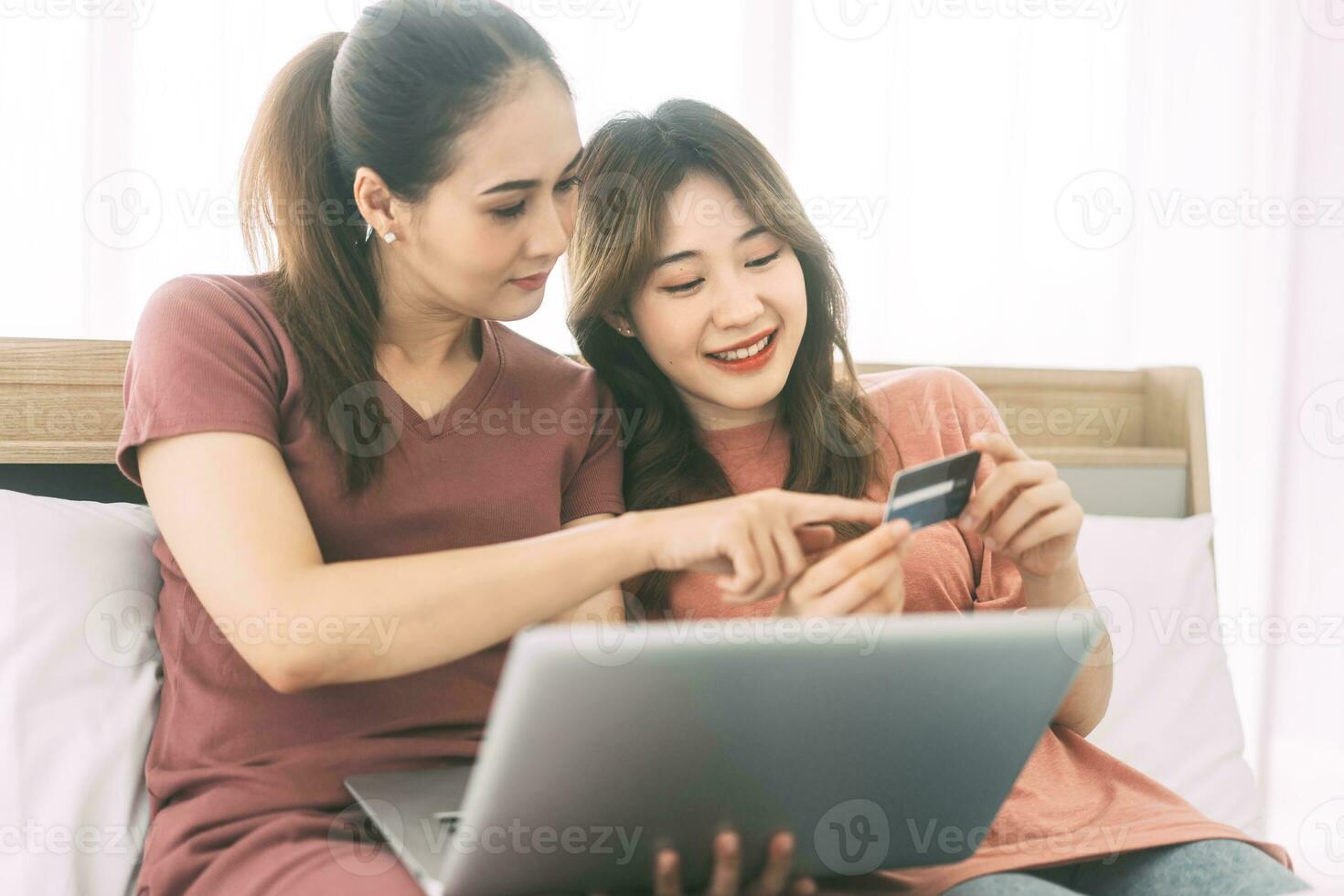 Two young adult woman living together with relationship laying at bedroom talking in the morning photo