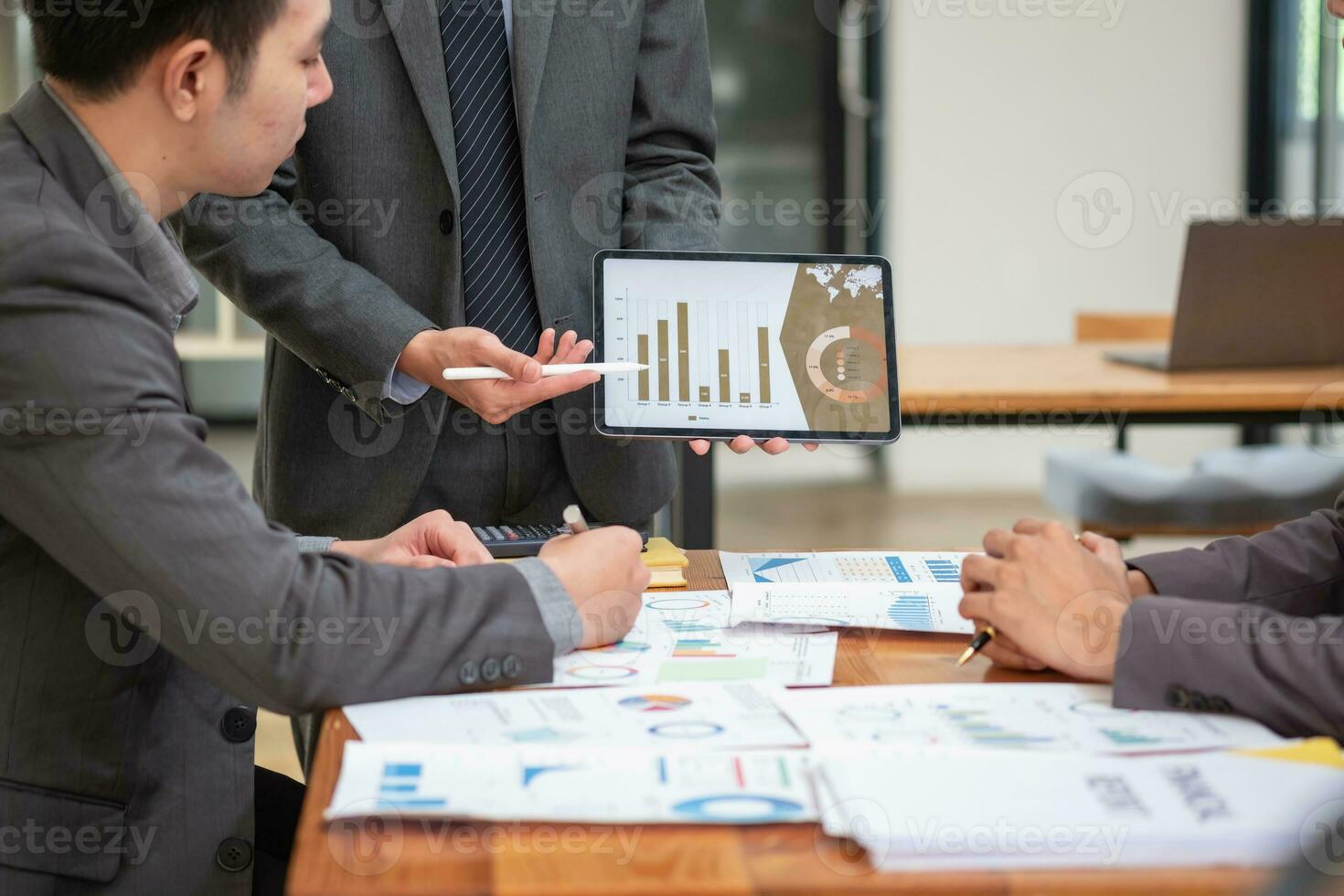 Asian business team consists of marketing staff. accountant and financial officer Help each other analyze company profits using tablets. calculator Laptop computers, graph paper, and corporate pens. photo