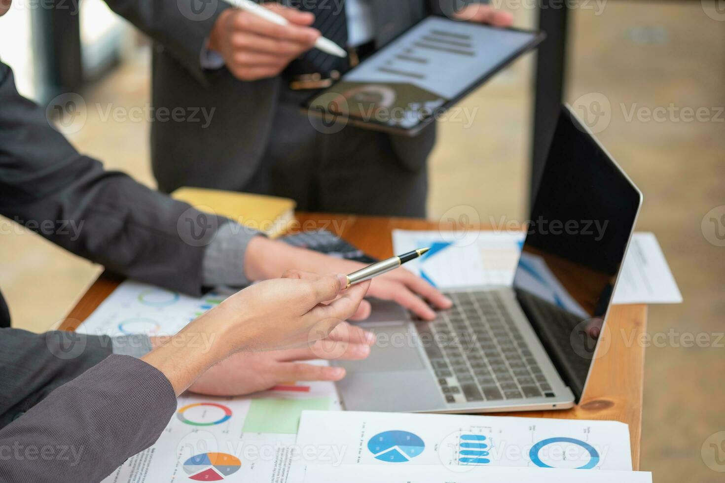 Asian business team consists of marketing staff. accountant and financial officer Help each other analyze company profits using tablets. calculator Laptop computers, graph paper, and corporate pens. photo