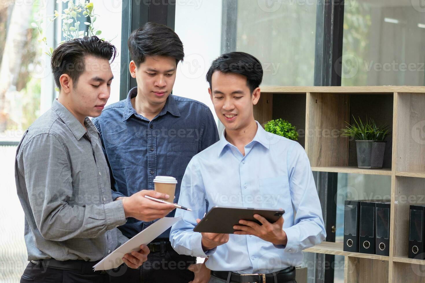 Asian business team consists of marketing staff. accountant and financial officer Help each other analyze company profits using tablets. calculator Laptop computers, graph paper, and corporate pens. photo