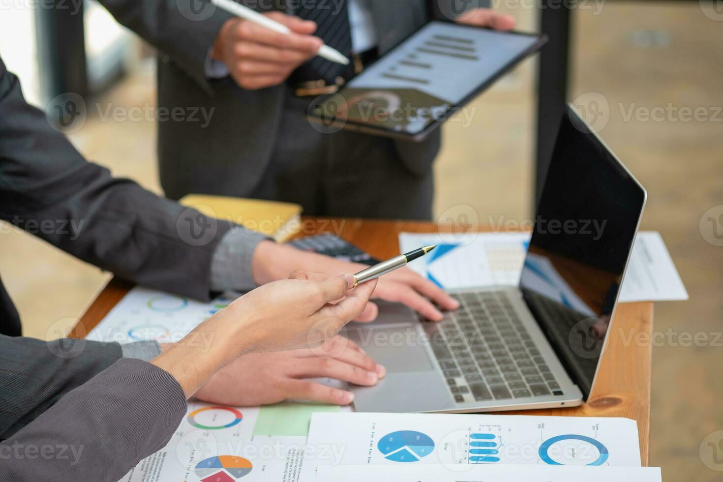 Asian business team consists of marketing staff. accountant and financial officer Help each other analyze company profits using tablets. calculator Laptop computers, graph paper, and corporate pens. photo