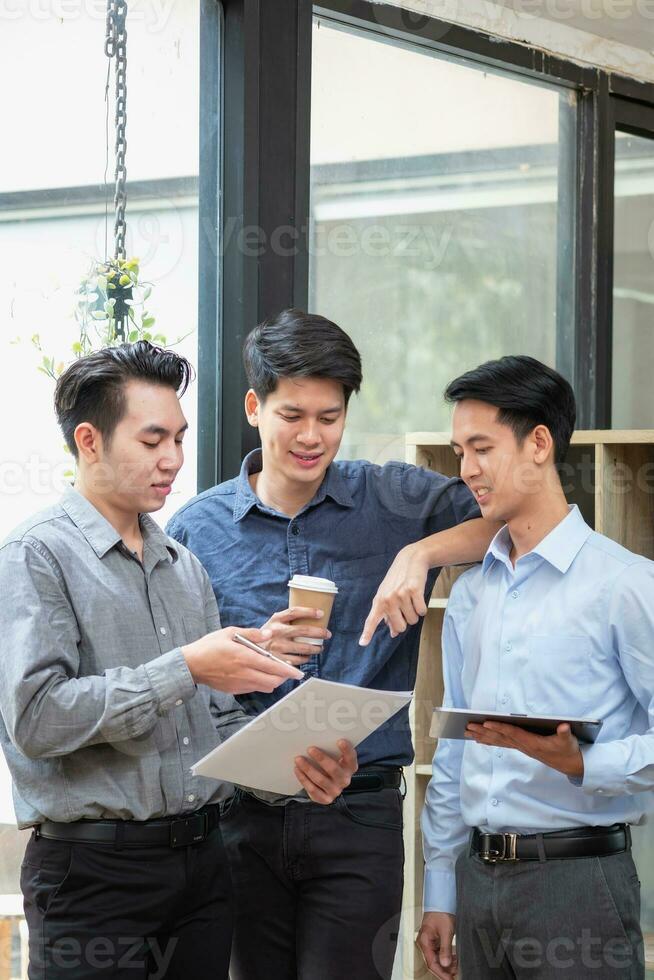 Asian business team consists of marketing staff. accountant and financial officer Help each other analyze company profits using tablets. calculator Laptop computers, graph paper, and corporate pens. photo