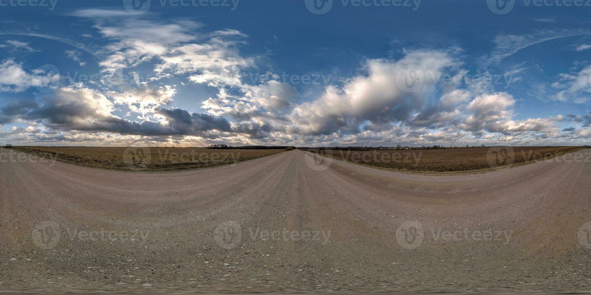 evening 360 hdri panorama on gravel road with clouds on blue sky before sunset in equirectangular spherical seamless projection, use as sky replacement in drone panoramas, game development as sky dome photo