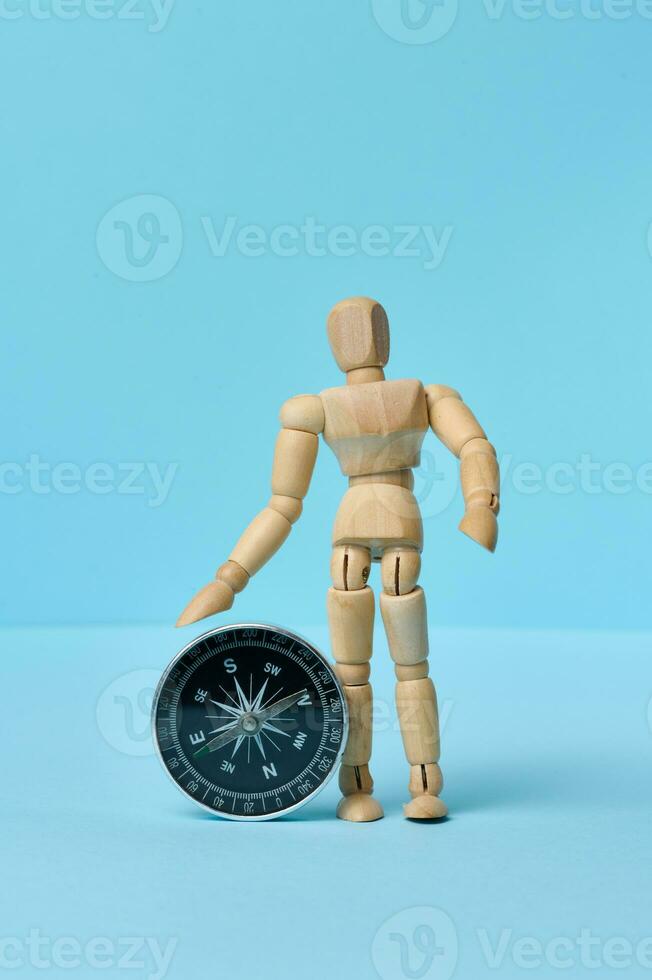 Wooden mannequin and round compass on a blue background photo