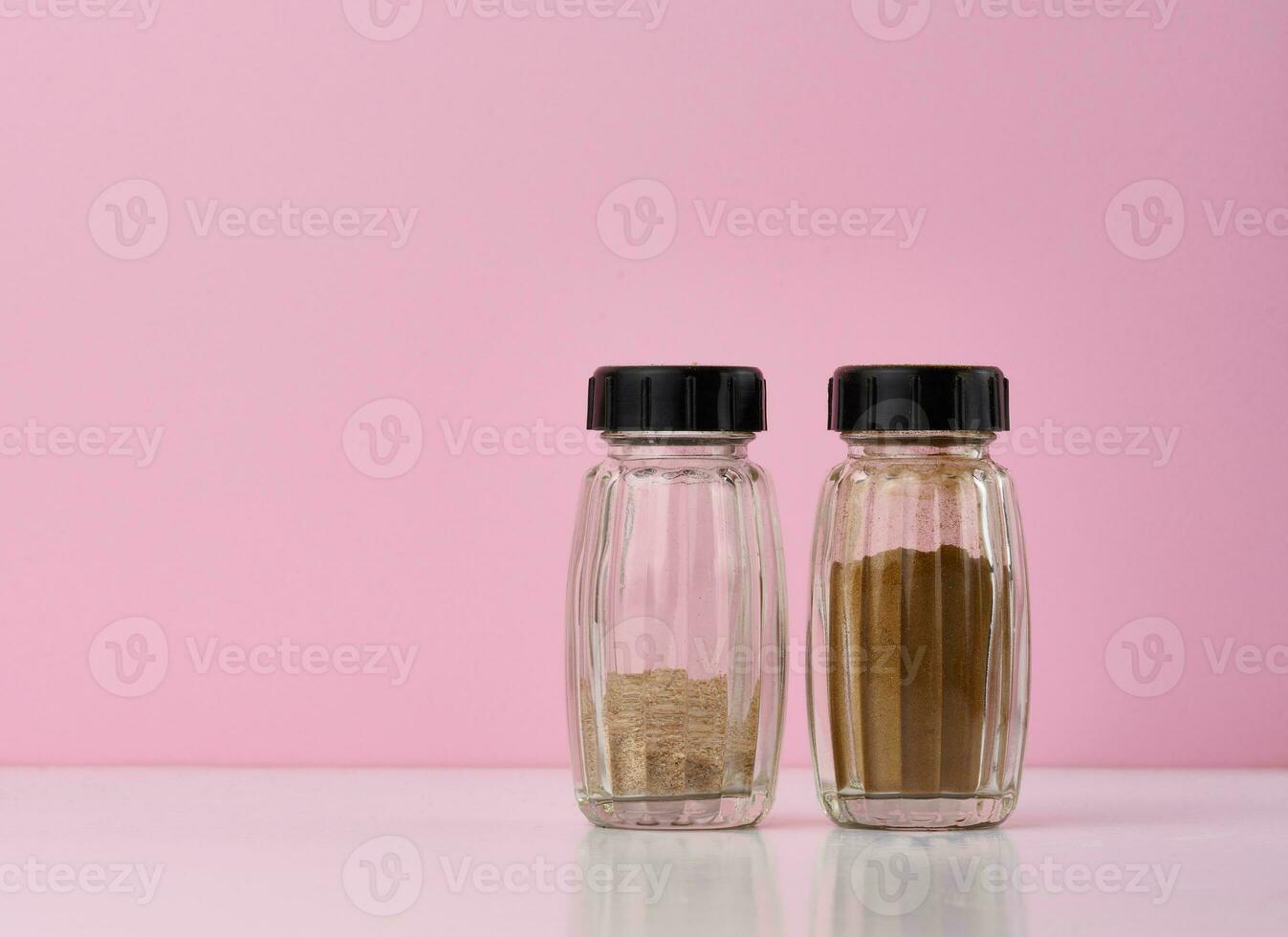 Transparent glass jar with ground cinnamon on a blue background, spice photo