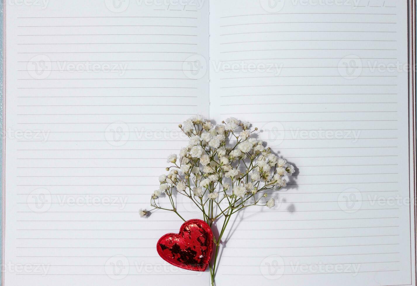 Empty white sheet of paper and gypsophila flowers on a pink background, space for an inscription photo