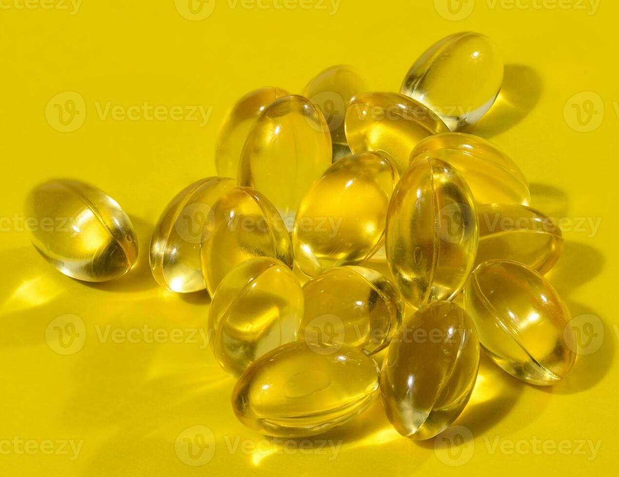 Yellow capsules with fish oil on a yellow background, close up photo