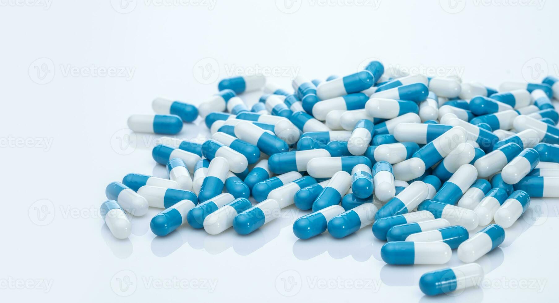 Pile of blue and white capsule pills. Pharmacy product. Prescription drug. Healthcare and medicine. Pharmaceutical industry. Pharmaceutical science. Prescription medication. Capsule pill production. photo