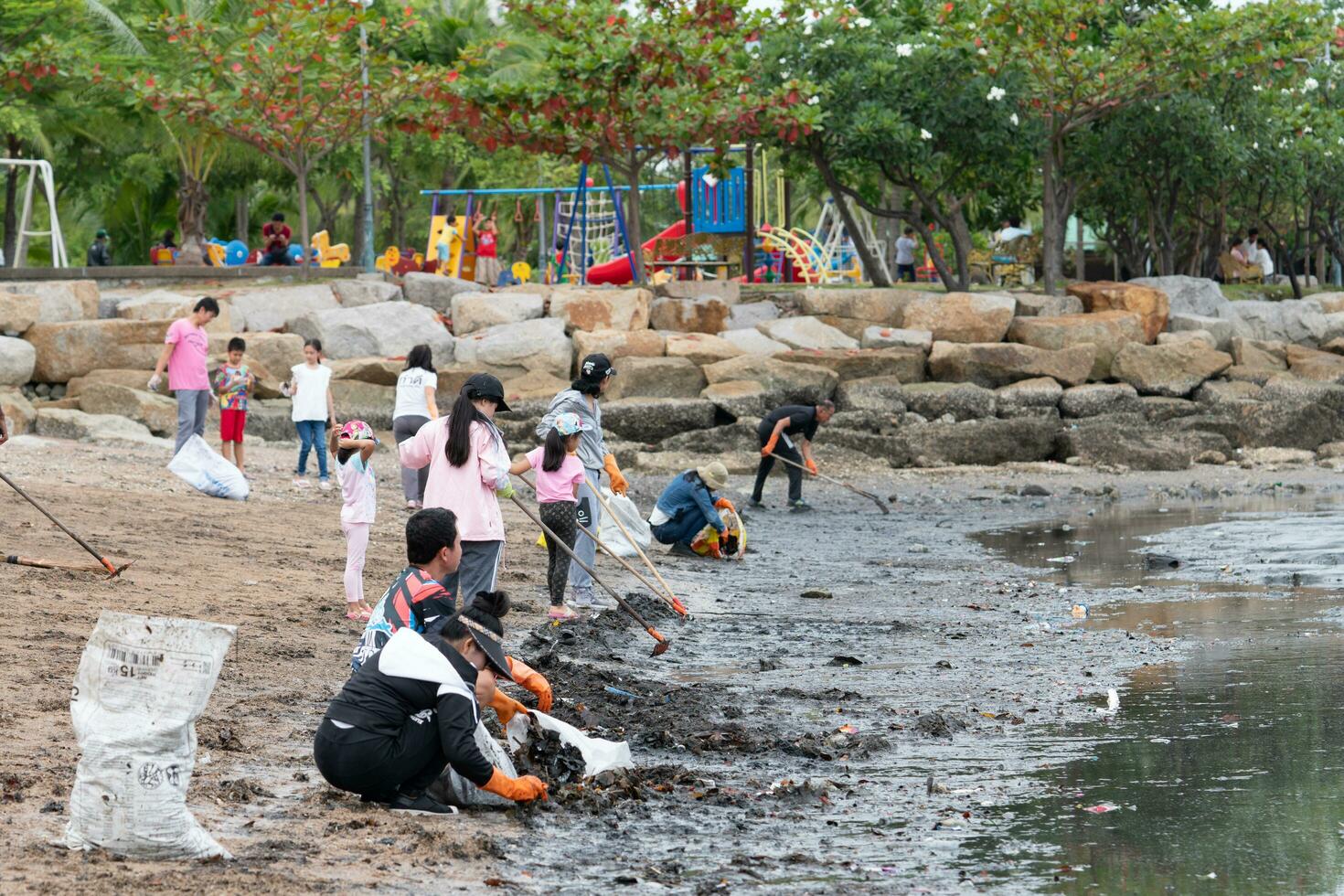 CHONBURI, THAILAND-AUGUST 13, 2018 Volunteer cleaning beach. Beach environment pollution. Children and parents pick up garbage at sand beach. Family outdoor activity for a charity event. Teamwork. photo