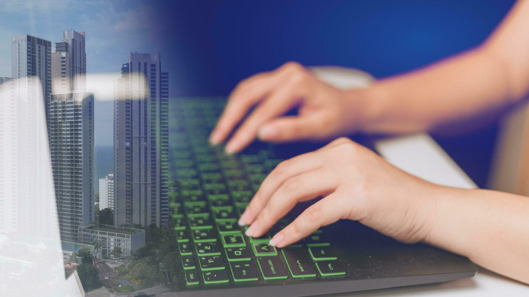 Hand of businesswoman typing on computer keyboard with cityscape on background photo