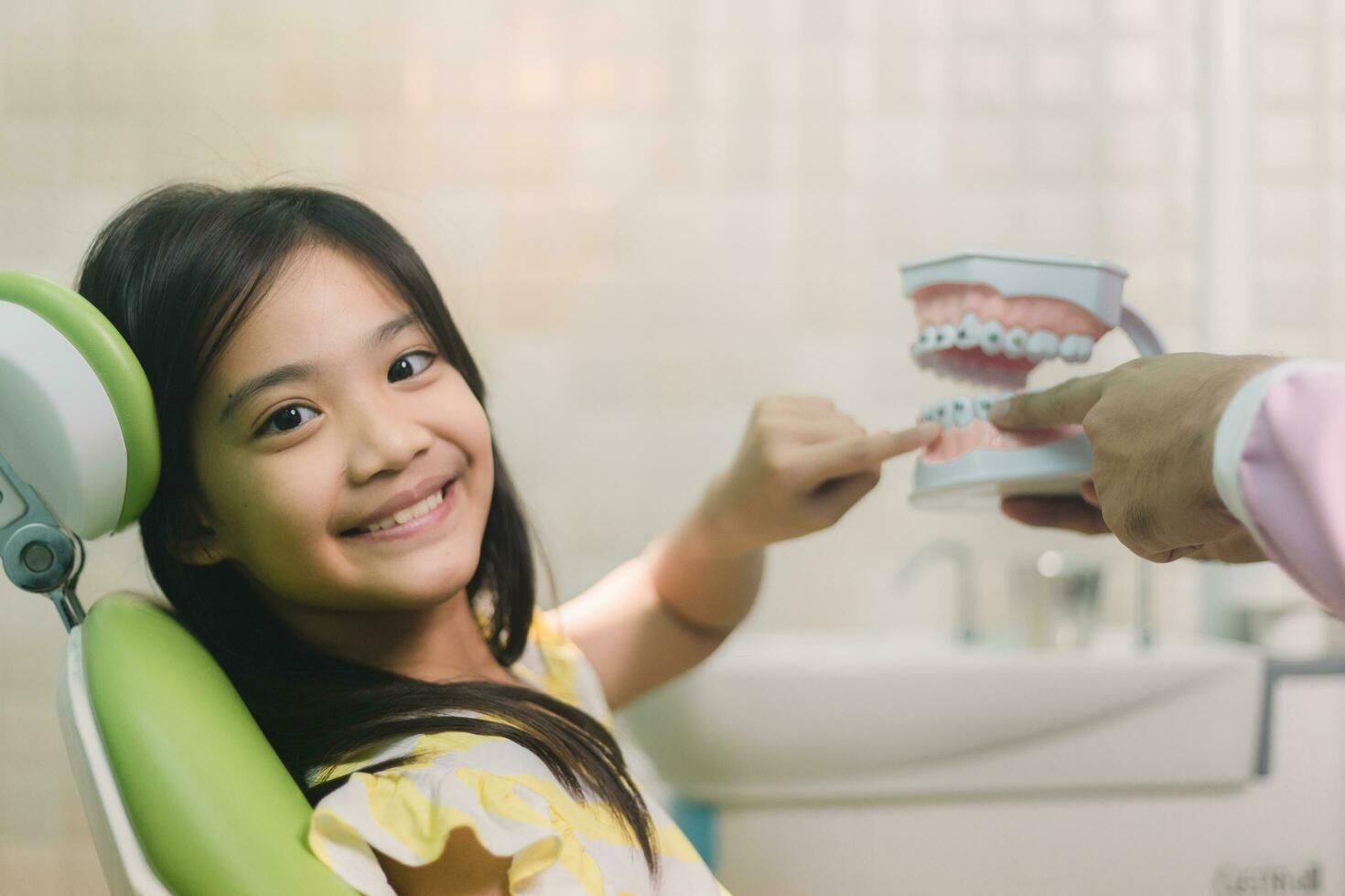 asiático masculino dentista demostración niños dientes modelo en clínica foto