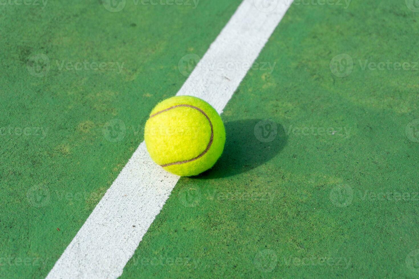 amarillo tenis pelota en verde Corte y blanco líneas. parte superior ángulo ver de tenis pelota en corte. foto