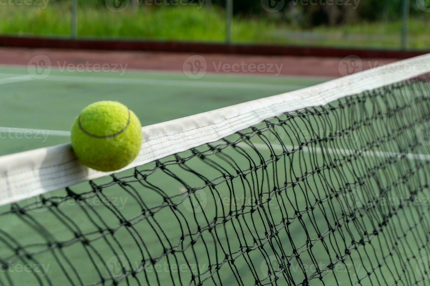 cerca arriba de tenis pelota clips el parte superior de el neto. tenis pelota golpear el red y va a el otro lado. foto